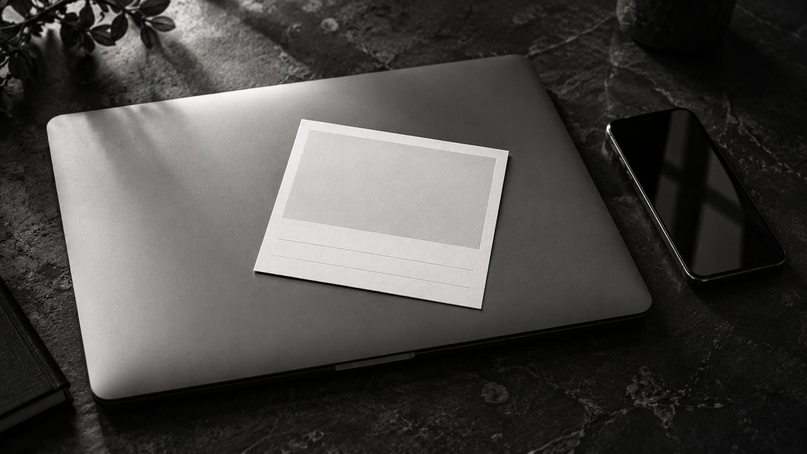Una notebook cerrada con una tarjeta en blanco apoyada encima, como la vista previa de un link, y un celular al lado.
